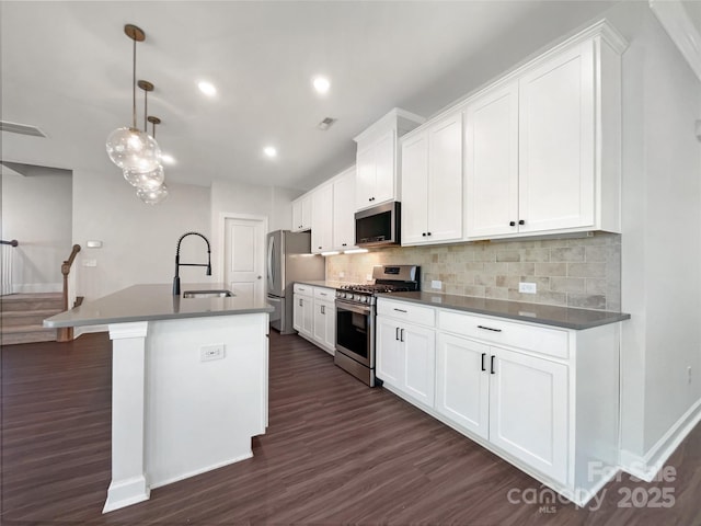 kitchen featuring sink, appliances with stainless steel finishes, white cabinetry, an island with sink, and decorative light fixtures