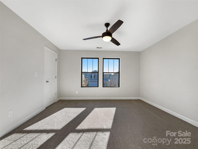 spare room featuring dark carpet and ceiling fan