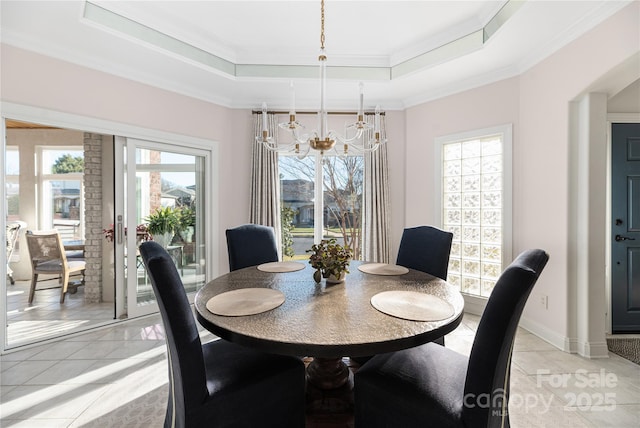 dining space with light tile patterned floors, a tray ceiling, and ornamental molding