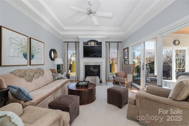 living room with crown molding, ceiling fan, and a raised ceiling