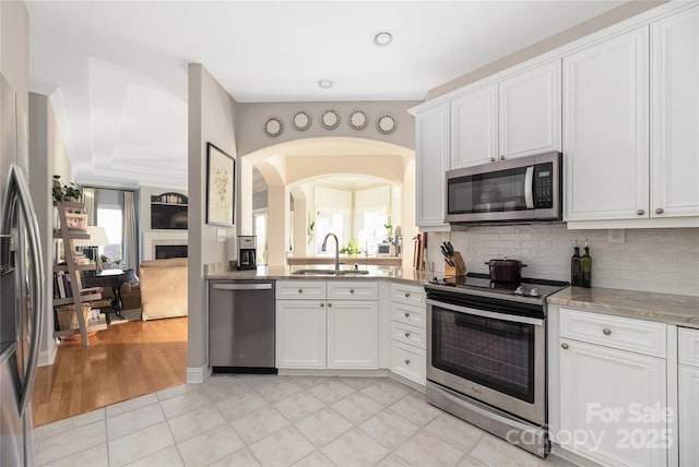 kitchen featuring sink, light tile patterned floors, stainless steel appliances, tasteful backsplash, and white cabinets