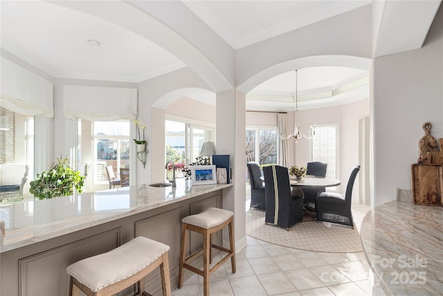 kitchen featuring light stone counters, sink, a healthy amount of sunlight, and a kitchen bar