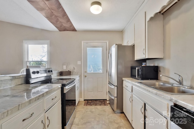 kitchen featuring stainless steel appliances, white cabinets, a sink, and light stone counters