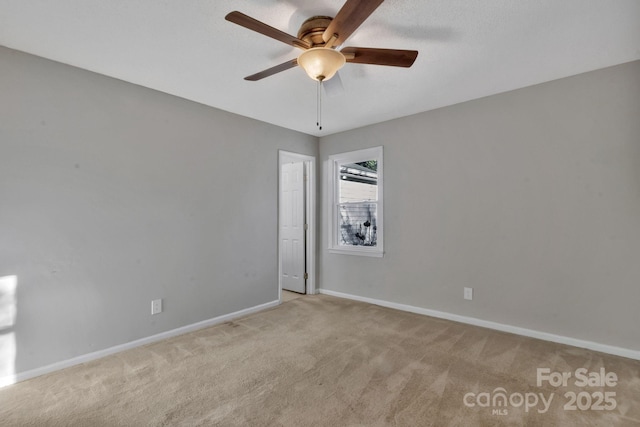 spare room with light carpet, ceiling fan, and baseboards