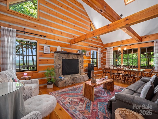 living room featuring hardwood / wood-style flooring, beamed ceiling, a stone fireplace, and a chandelier