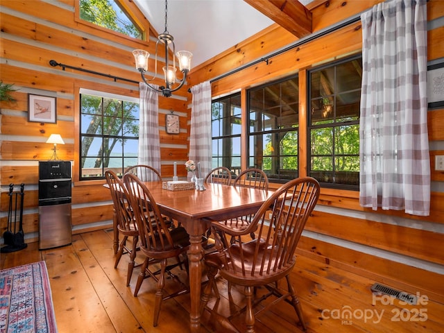 dining space featuring light hardwood / wood-style floors, a chandelier, and vaulted ceiling with beams