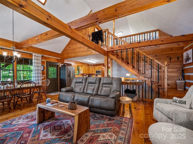 living room featuring high vaulted ceiling, wood walls, hardwood / wood-style floors, and an inviting chandelier