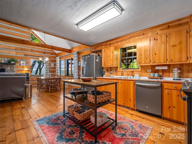 kitchen with wood walls, light hardwood / wood-style flooring, appliances with stainless steel finishes, and a healthy amount of sunlight