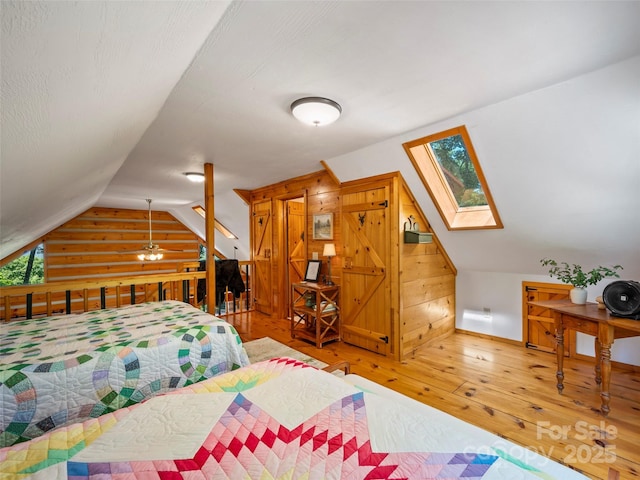 bedroom featuring hardwood / wood-style floors, wooden walls, and lofted ceiling with skylight