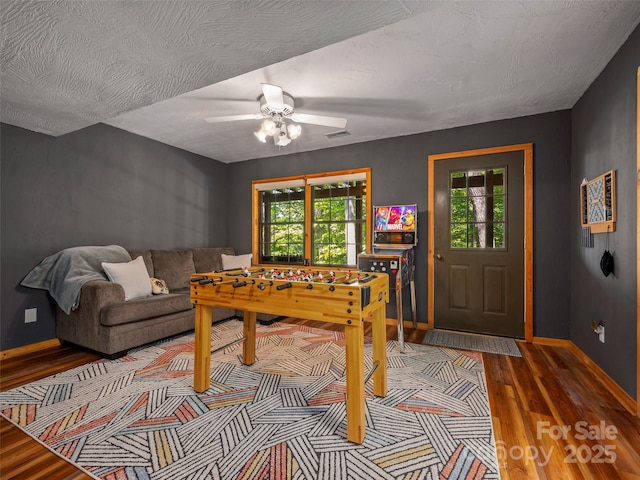 game room with hardwood / wood-style floors, a textured ceiling, and ceiling fan