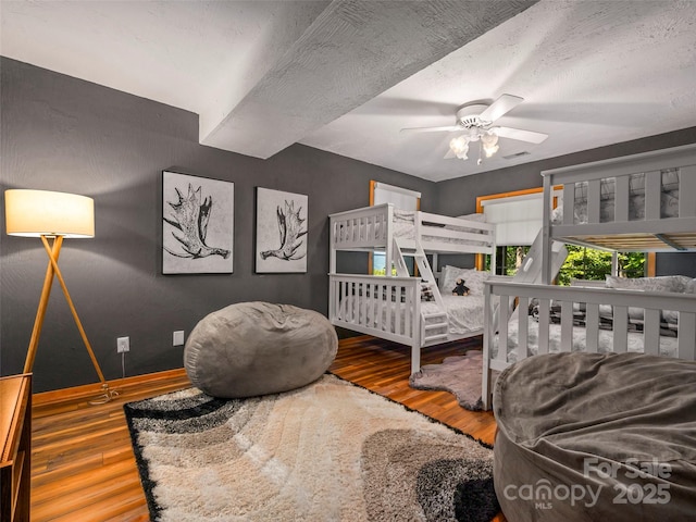 bedroom with ceiling fan, wood-type flooring, and a textured ceiling