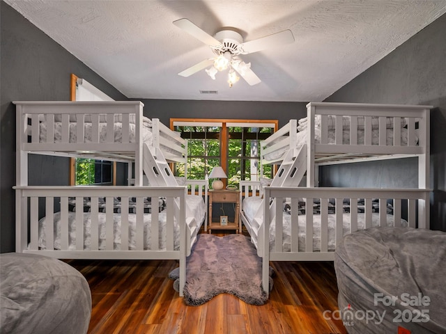 bedroom with ceiling fan, dark wood-type flooring, and a textured ceiling