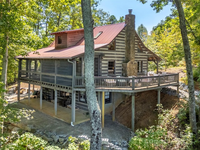 rear view of property featuring a wooden deck, a sunroom, and a patio