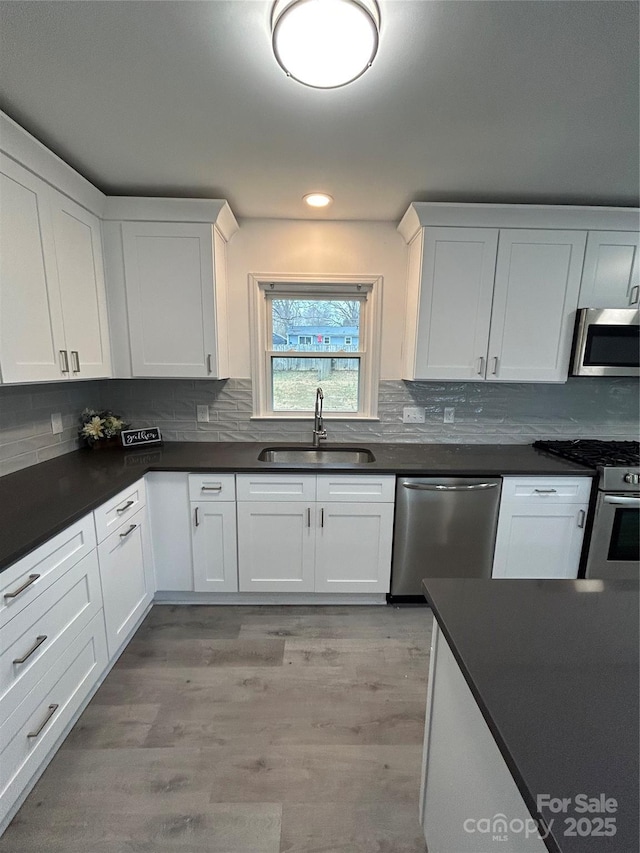 kitchen featuring sink, stainless steel appliances, light hardwood / wood-style floors, and white cabinets