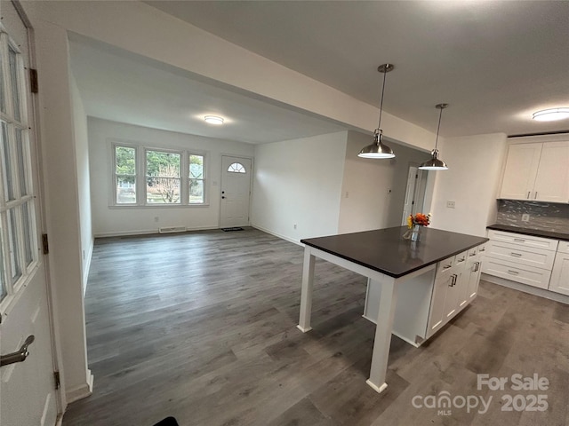 kitchen featuring a breakfast bar, pendant lighting, dark hardwood / wood-style floors, white cabinets, and backsplash