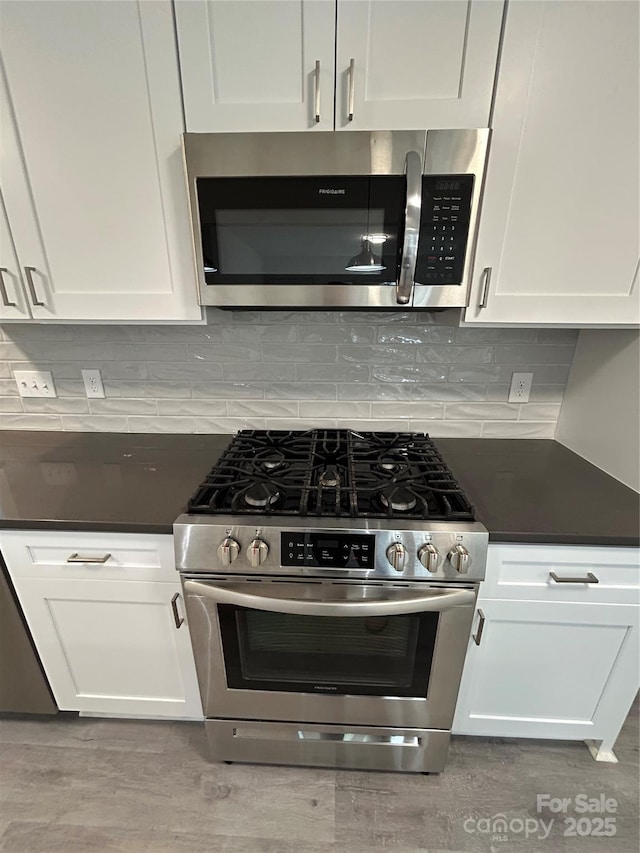 kitchen with stainless steel appliances, light hardwood / wood-style floors, decorative backsplash, and white cabinets