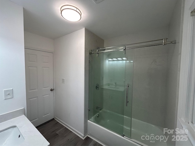 bathroom featuring hardwood / wood-style flooring, vanity, and shower / bath combination with glass door