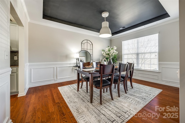 dining room featuring ornamental molding, dark wood-type flooring, and a tray ceiling