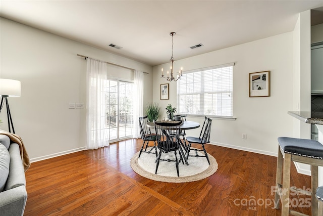 dining room with dark wood-type flooring and an inviting chandelier