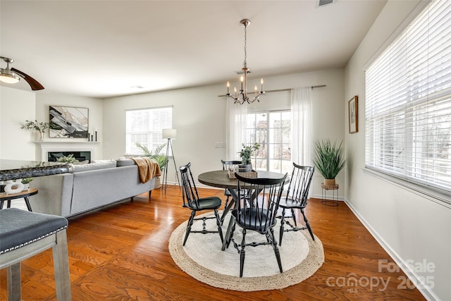 dining space with hardwood / wood-style flooring, a healthy amount of sunlight, and an inviting chandelier