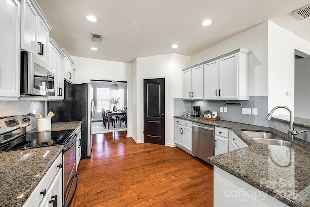 kitchen with white cabinetry, sink, stainless steel appliances, and dark stone counters