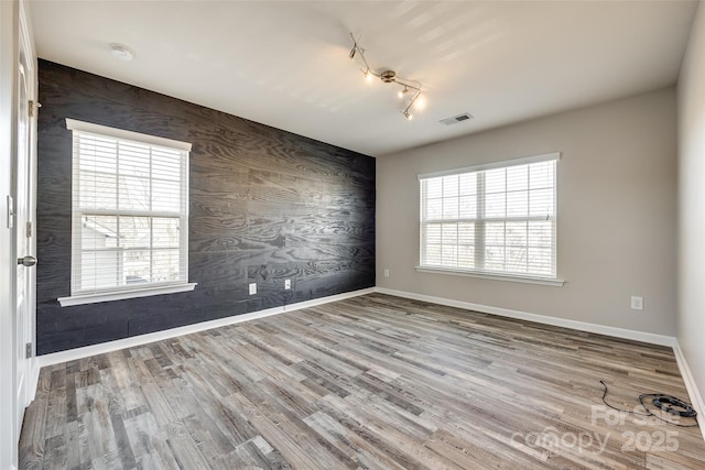 unfurnished room with wood-type flooring, rail lighting, and a healthy amount of sunlight