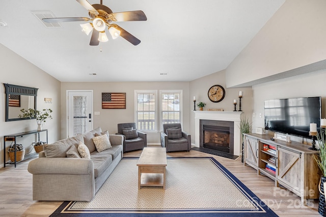 living room with vaulted ceiling, light hardwood / wood-style floors, and ceiling fan