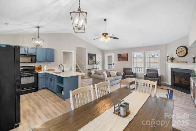 dining space featuring ceiling fan, lofted ceiling, sink, and light hardwood / wood-style floors