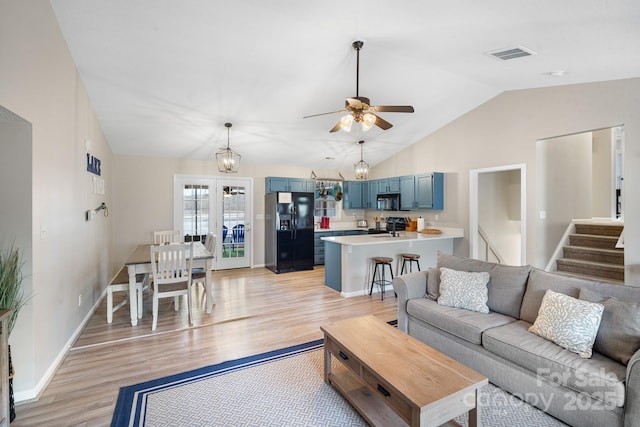 living room with lofted ceiling, ceiling fan with notable chandelier, and light hardwood / wood-style floors