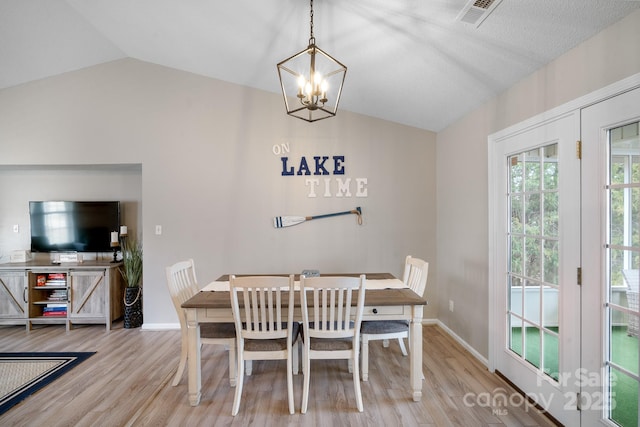 dining space featuring lofted ceiling, a chandelier, and light wood-type flooring