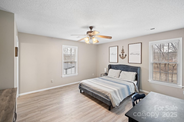 bedroom featuring a textured ceiling, ceiling fan, and light wood-type flooring