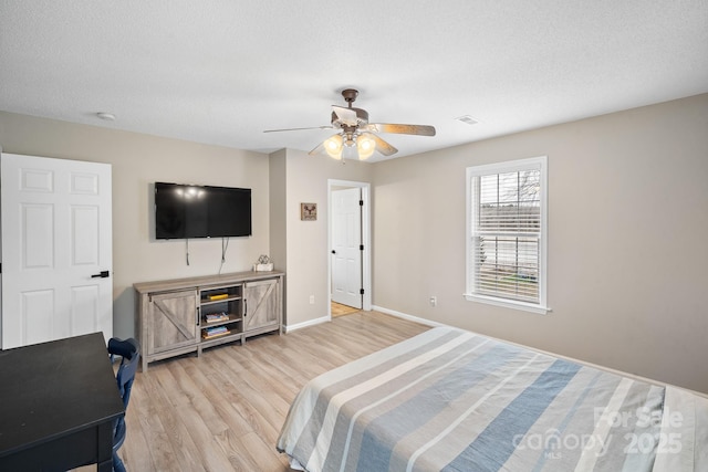 bedroom with a textured ceiling, light hardwood / wood-style flooring, and ceiling fan