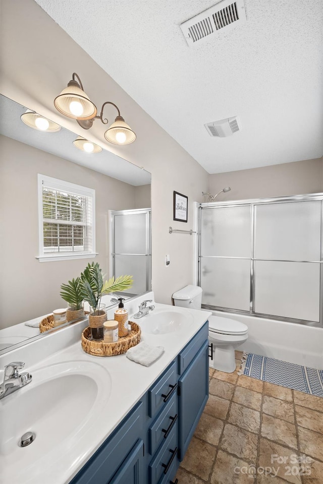 full bathroom featuring toilet, vanity, shower / bath combination with glass door, and a textured ceiling