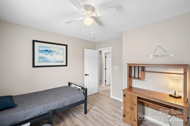 bedroom with ceiling fan, light hardwood / wood-style floors, and a textured ceiling