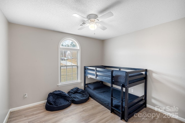 bedroom featuring hardwood / wood-style flooring, a textured ceiling, and ceiling fan