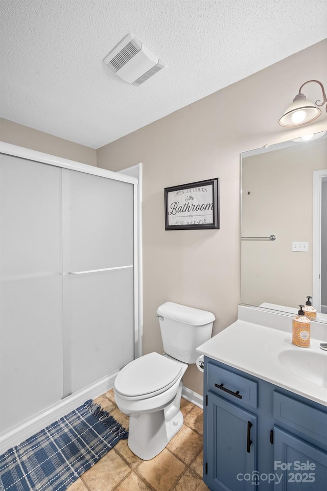 bathroom featuring vanity, toilet, a shower with door, and a textured ceiling