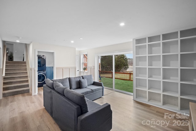 living room with stacked washer / drying machine and light wood-type flooring