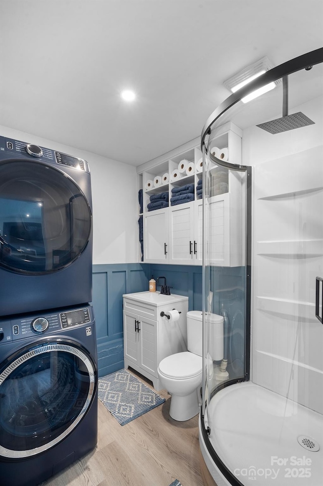 bathroom featuring stacked washer and dryer, wood-type flooring, a shower with shower door, and vanity