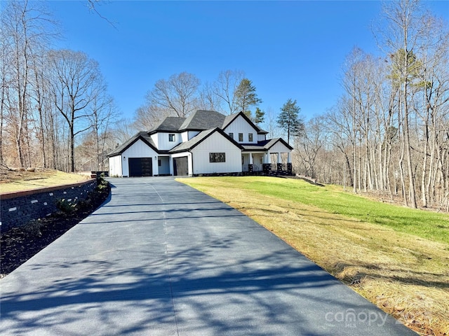 view of front of house with driveway, a front lawn, board and batten siding, and roof with shingles