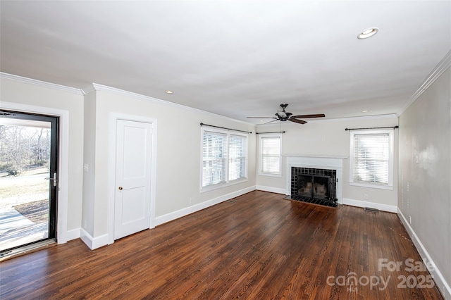 unfurnished living room with crown molding, a tile fireplace, dark hardwood / wood-style floors, and ceiling fan