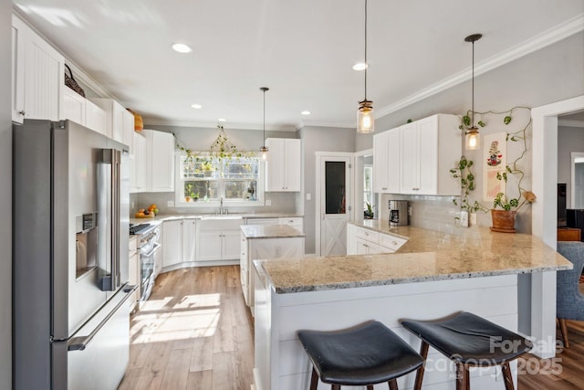 kitchen featuring a kitchen bar, high end appliances, kitchen peninsula, pendant lighting, and white cabinets