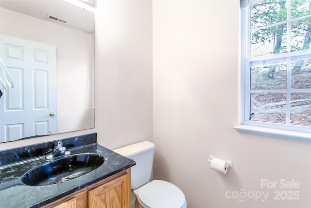 bathroom featuring vanity, a wealth of natural light, and toilet