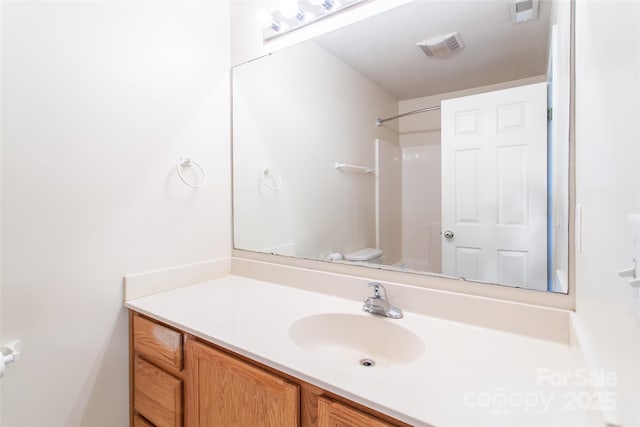 bathroom featuring vanity, a shower, and toilet