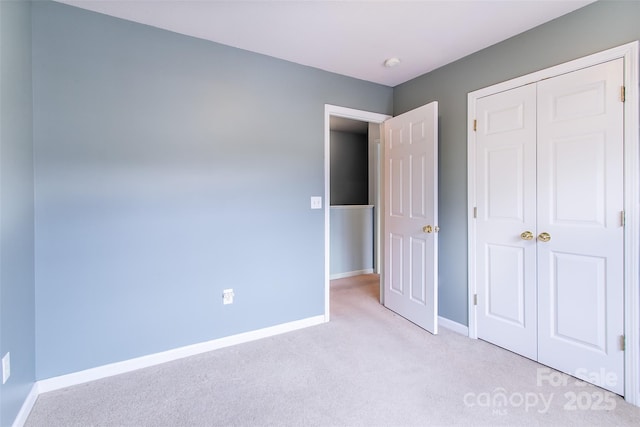 unfurnished bedroom with light colored carpet and a closet