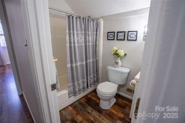 bathroom featuring toilet, hardwood / wood-style floors, and shower / tub combo with curtain