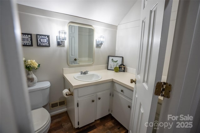 bathroom featuring vanity, toilet, hardwood / wood-style floors, and lofted ceiling