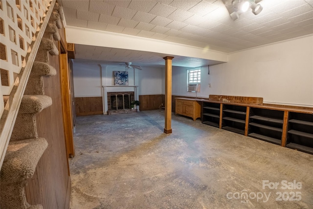 basement with ceiling fan, cooling unit, and wooden walls