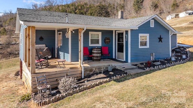 back of property with a lawn and a porch