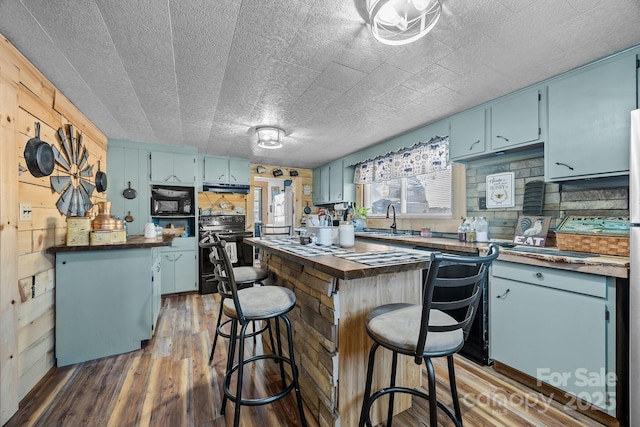 kitchen featuring black appliances, butcher block counters, and blue cabinets