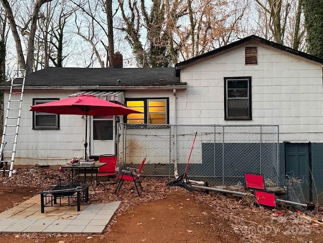 rear view of property featuring a fire pit and a patio